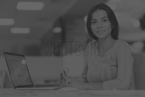 Woman smiling at desk with laptop.